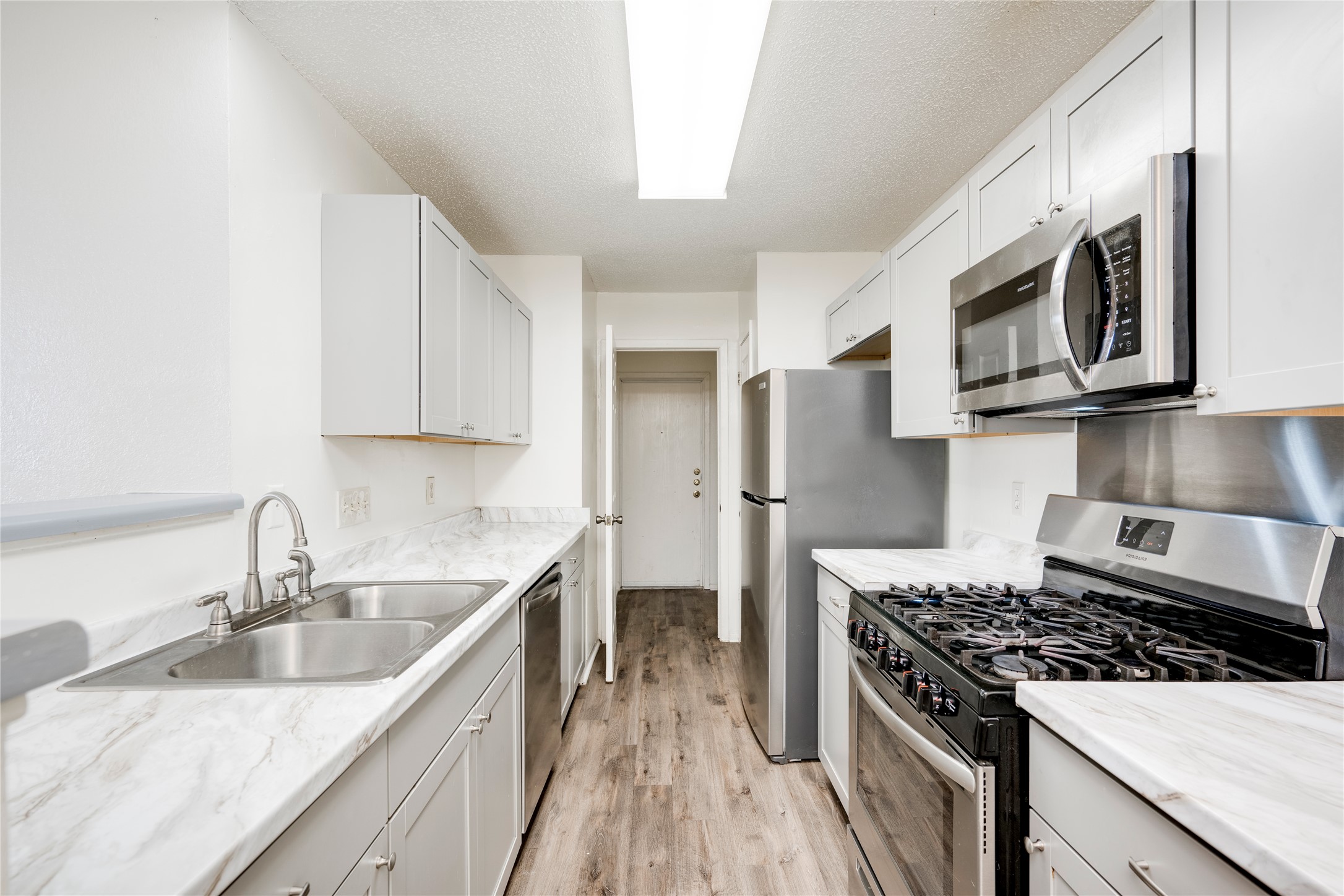 7918 West Gate Boulevard Austin, TX 78745 - Photo 20 of 31 A galley kitchen with abundant light offers efficient meal preparation and a fresh aesthetic.