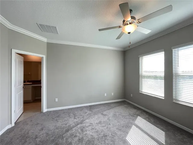 a view of an empty room with chandelier fan and fire place
