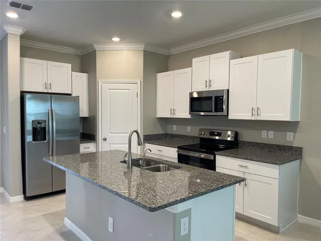 a kitchen with stainless steel appliances granite countertop a sink a stove and a refrigerator