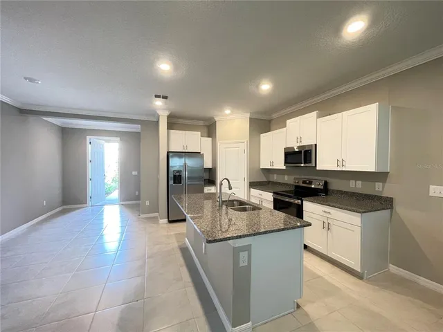 a large kitchen with kitchen island a sink a counter top space appliances and cabinets