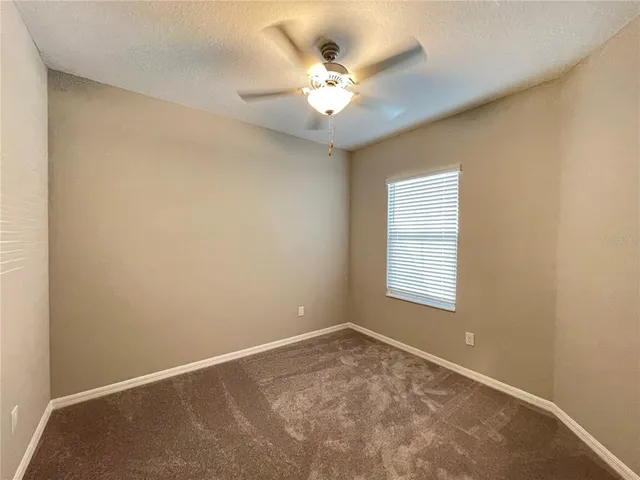 an empty room with a window and a ceiling fan