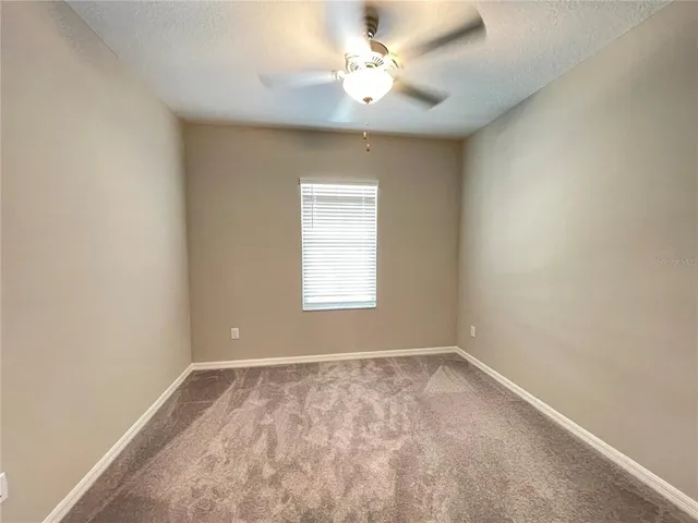 an empty room with a window and a fan