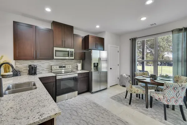 a kitchen with stainless steel appliances granite countertop sink stove refrigerator and cabinets