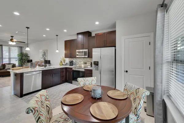 a kitchen with stainless steel appliances granite countertop a sink a stove a kitchen island with chairs and wooden floor