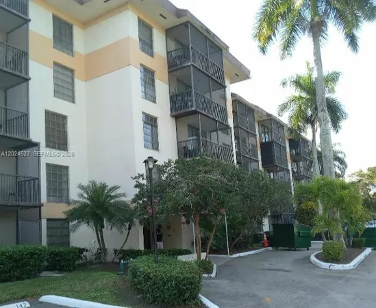 a view of a tall white building plants and palm trees