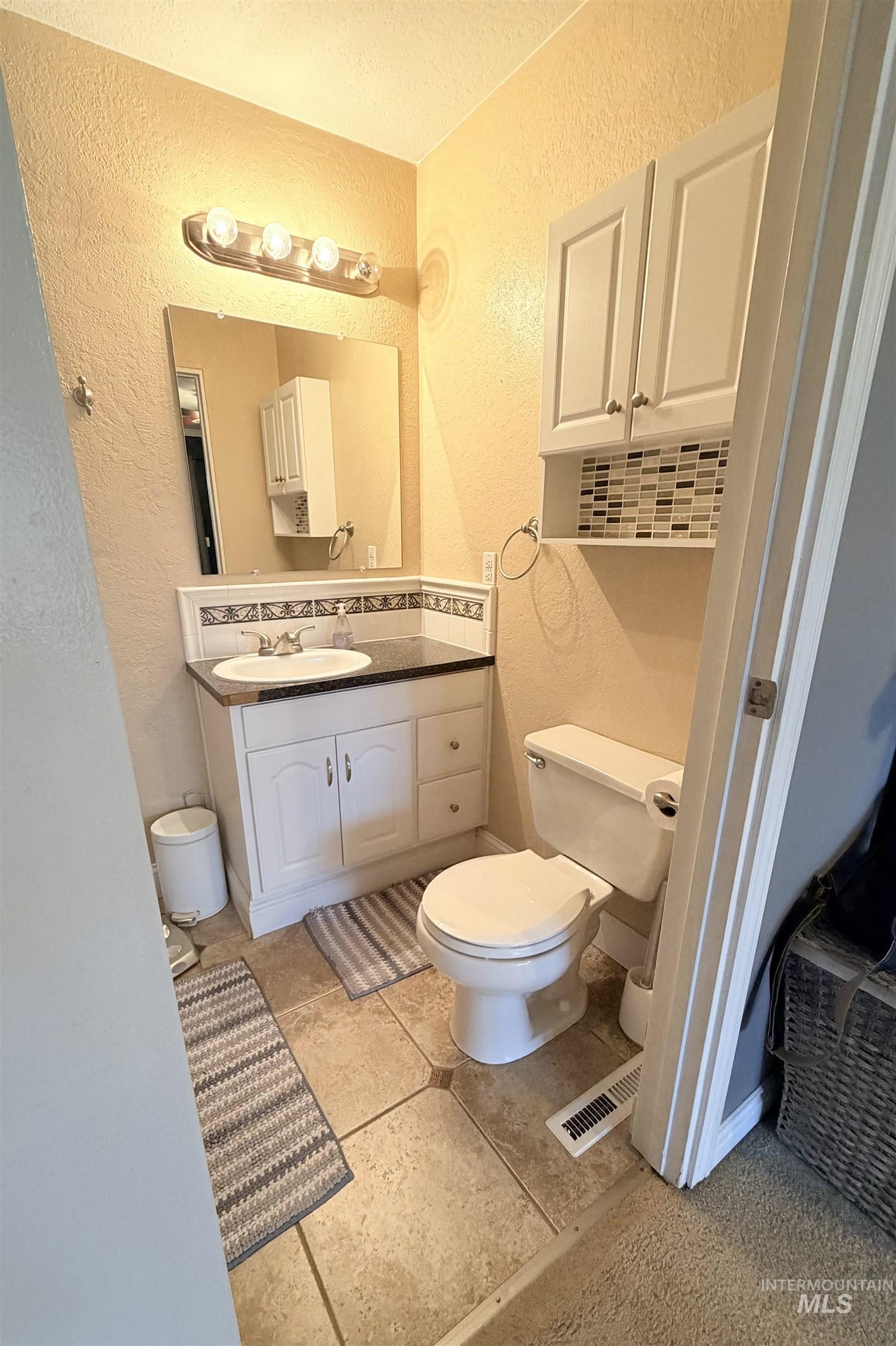 1306 Hemlock Avenue Lewiston, ID 83501 - Photo 12 of 38 Half bathroom with a textured wall, vanity, a textured ceiling, and backsplash