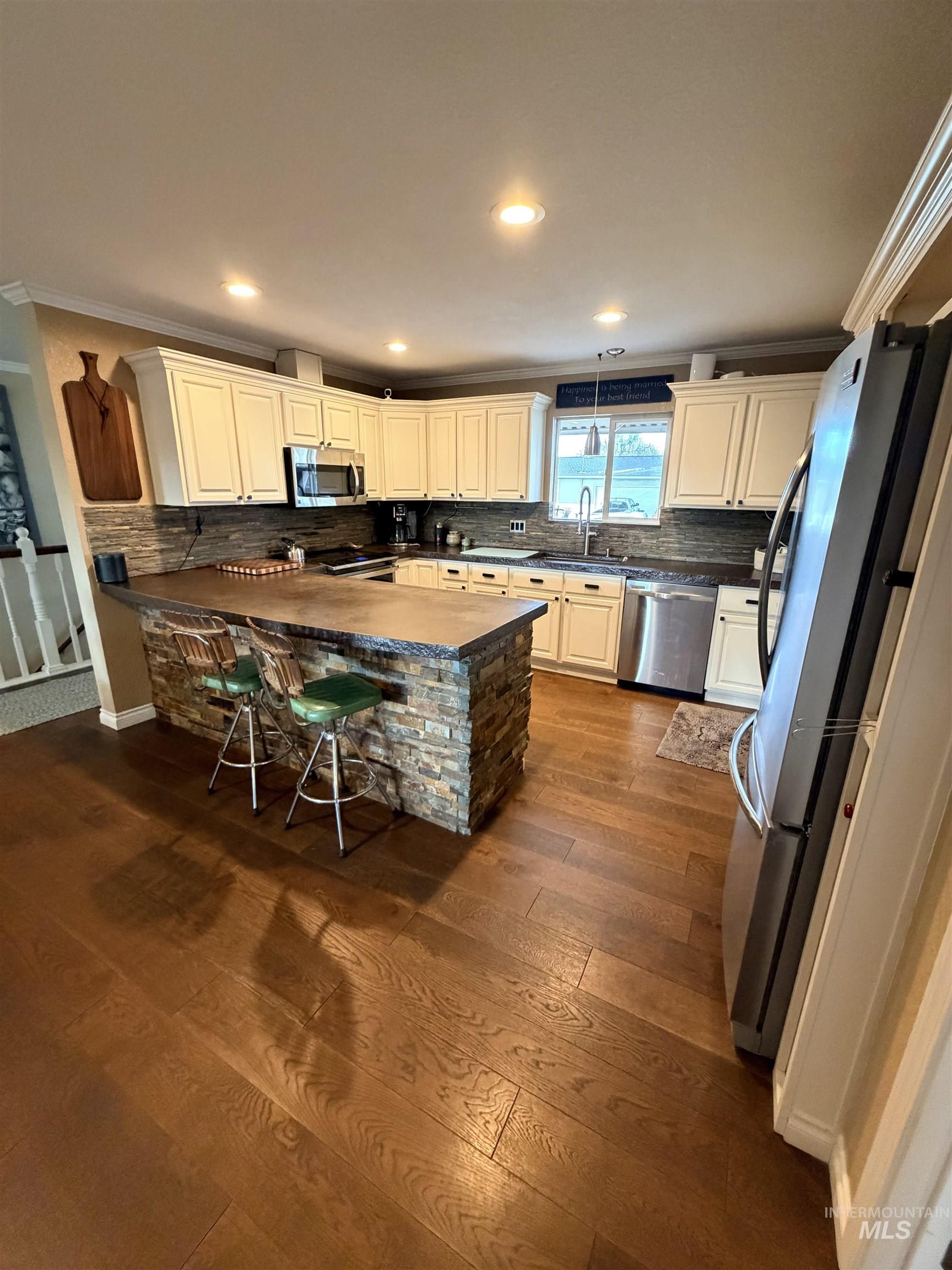 1306 Hemlock Avenue Lewiston, ID 83501 - Photo 9 of 38 Kitchen with stainless steel appliances, dark wood finished floors, backsplash, a kitchen bar, and recessed lighting