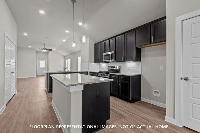 a kitchen with kitchen island stainless steel appliances a sink cabinets and a counter top space
