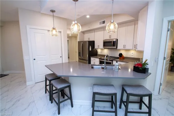 a kitchen with a dining table chairs cabinets and stainless steel appliances