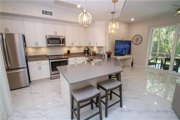 a kitchen with stainless steel appliances granite countertop a stove a refrigerator a kitchen island a sink a stove a dining table and chairs with wooden floor