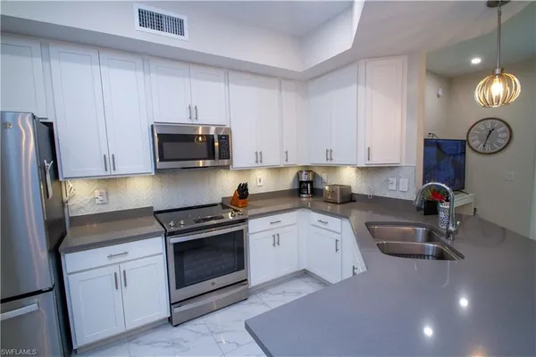 a kitchen with granite countertop a stove a sink and a microwave