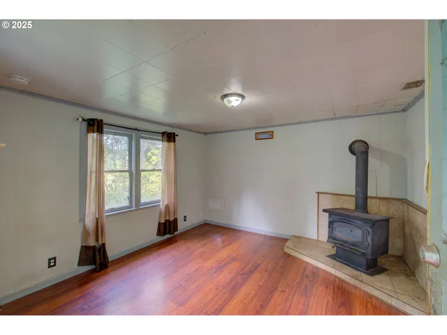 a view of an empty room with window and wooden floor