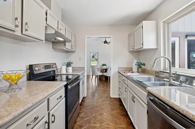 a kitchen with stainless steel appliances granite countertop a sink a stove top oven a counter space and cabinets