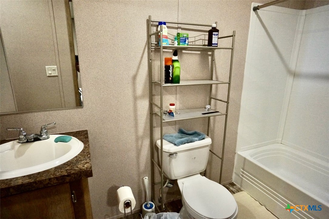 1502 West Monroe Avenue Port O'Connor, TX 77982 - Photo 21 of 22 a bathroom with a granite countertop toilet sink and mirror