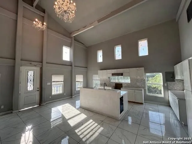 a large living room with stainless steel appliances kitchen island granite countertop furniture and a chandelier