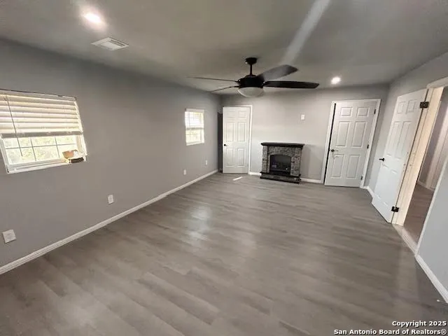 an empty room with wooden floor fireplace and windows