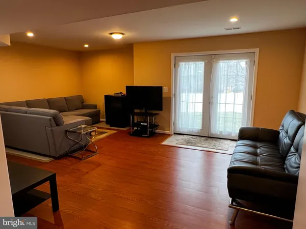 a living room with furniture a flat screen tv and wooden floor