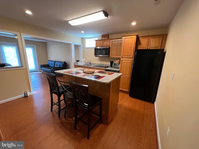 a kitchen with stainless steel appliances granite countertop a refrigerator a sink a stove a dining table and chairs