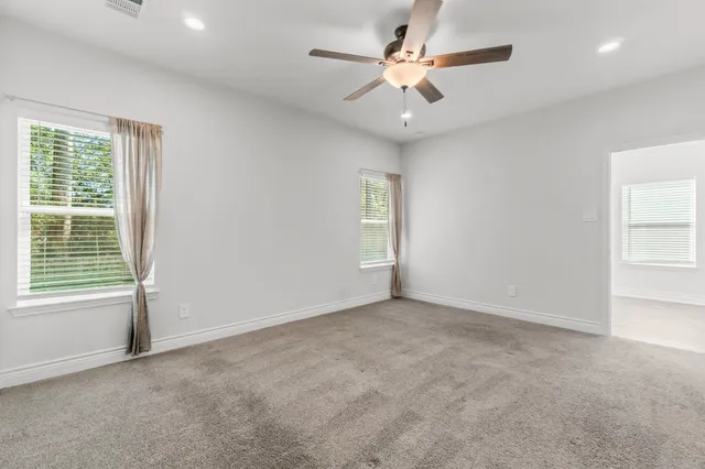 an empty room with windows and fan
