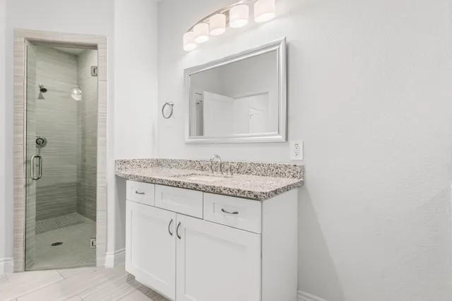 a bathroom with a granite countertop sink a mirror and a shower