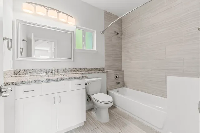 a bathroom with a granite countertop sink a mirror a toilet and bathtub