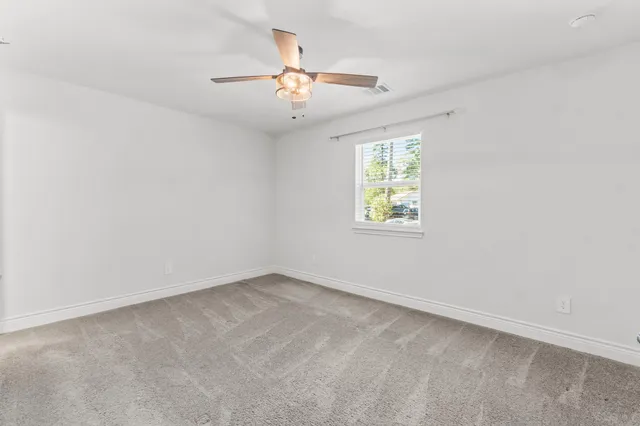 an empty room with windows and fan