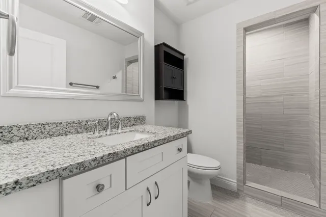 a bathroom with a granite countertop toilet sink and mirror