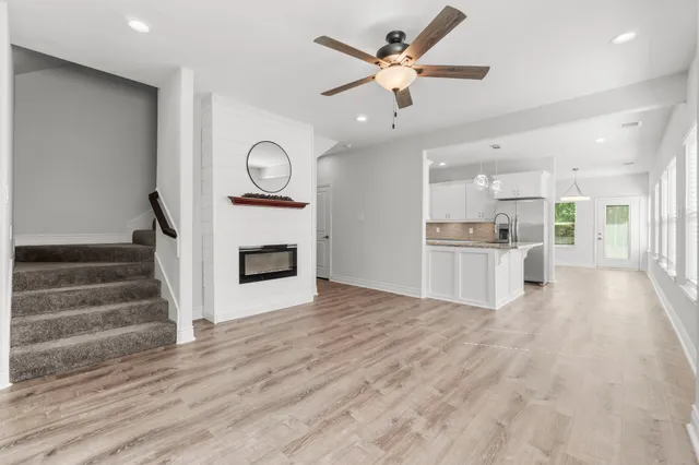 a view of kitchen and empty room with wooden floor