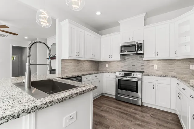 a kitchen with granite countertop a sink and stainless steel appliances