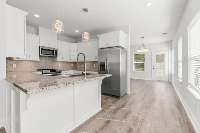 a kitchen with stainless steel appliances granite countertop a refrigerator a sink a stove a microwave and white cabinets