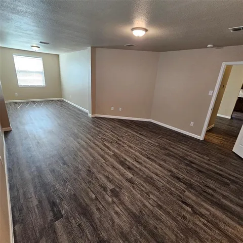 a view of an empty room with wooden floor and window