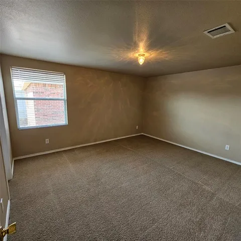 an empty room with a chandelier fan and windows