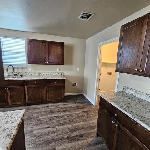 a kitchen with a granite countertop sink and cabinets