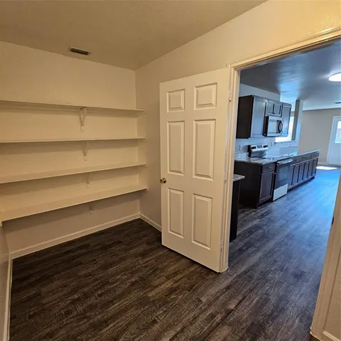 a large kitchen with a center island wooden floor and stainless steel appliances