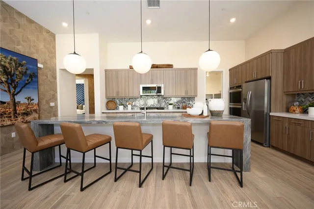 a kitchen with stainless steel appliances kitchen island granite countertop a table chairs and a refrigerator