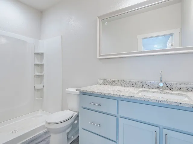a bathroom with a granite countertop sink toilet and shower