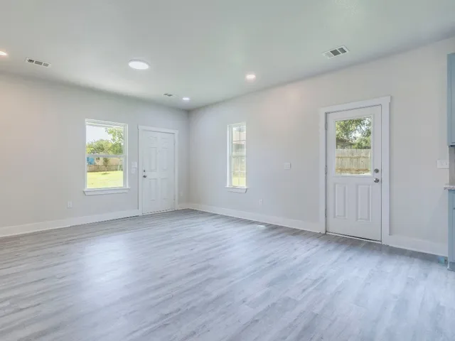 an empty room with wooden floor and windows