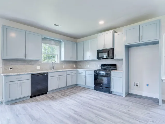 a kitchen with granite countertop white cabinets and stainless steel appliances