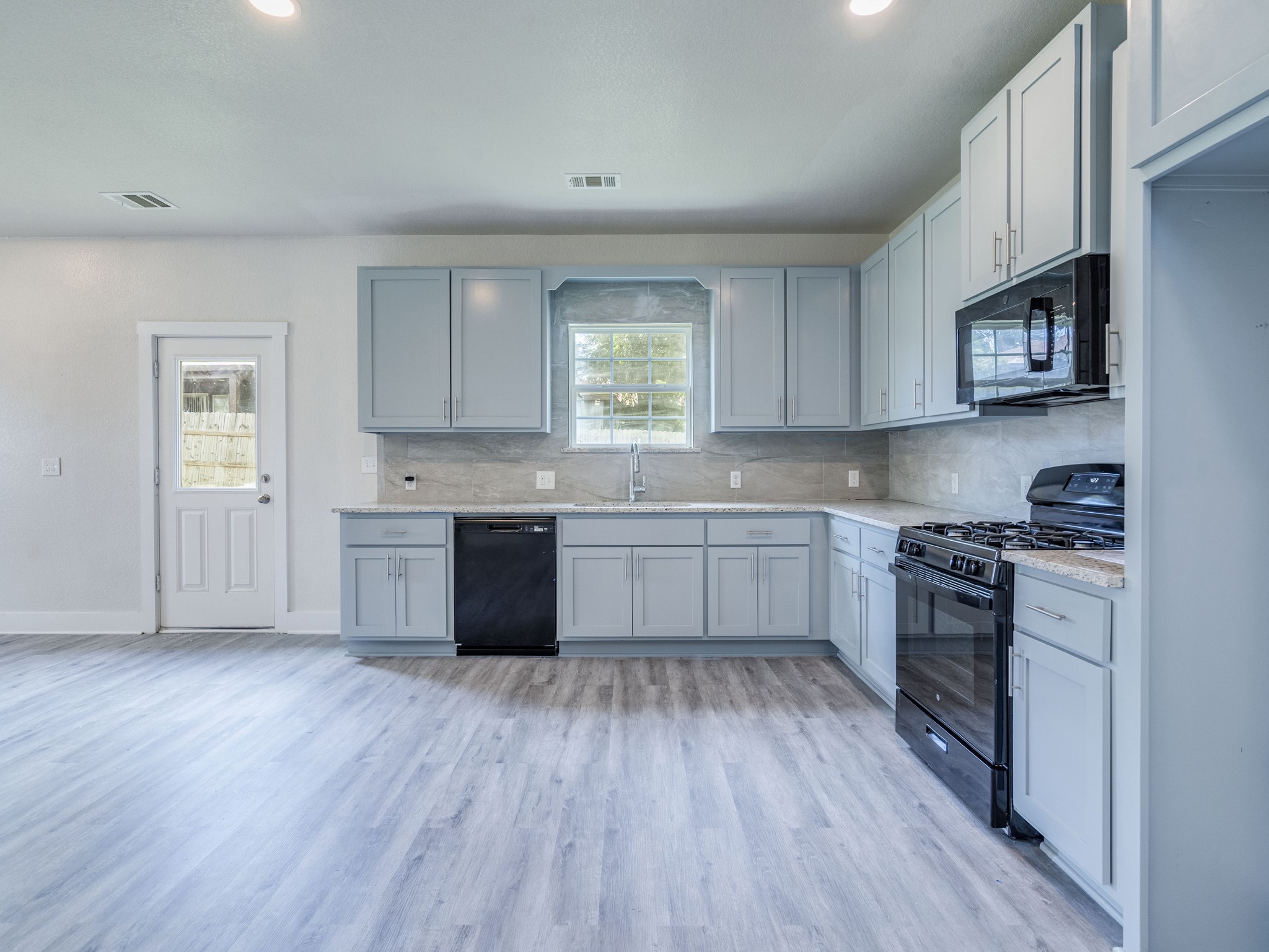 411 South Ave B Elgin, TX 78621 - Photo 8 of 23 a kitchen with stainless steel appliances sink cabinets and wooden floor