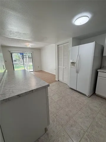 a view of a kitchen with refrigerator and more cabinets