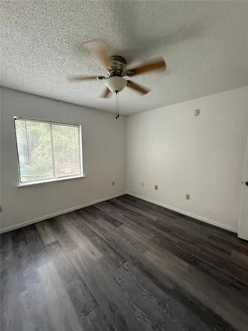 an empty room with wooden floor ceiling fan