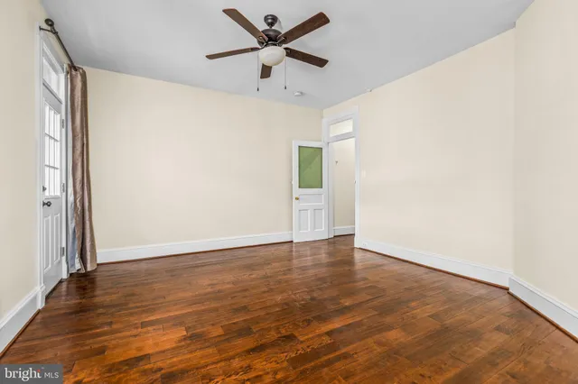 an empty room with wooden floor fan and windows