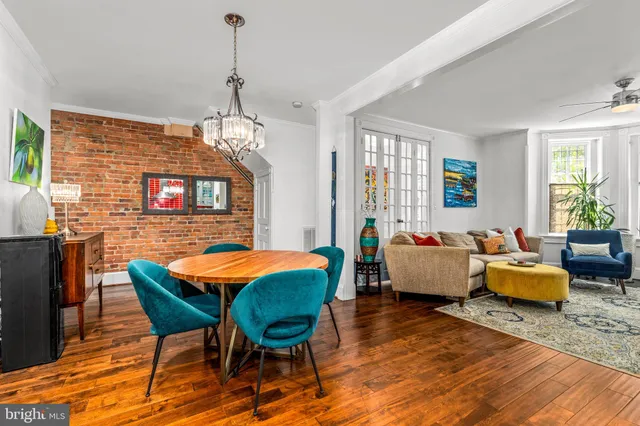 a dining room with wooden floor a chandelier a glass table and chairs