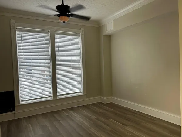 a view of an empty room with a window and wooden floor