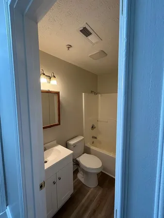 a bathroom with a granite countertop toilet a sink and a mirror