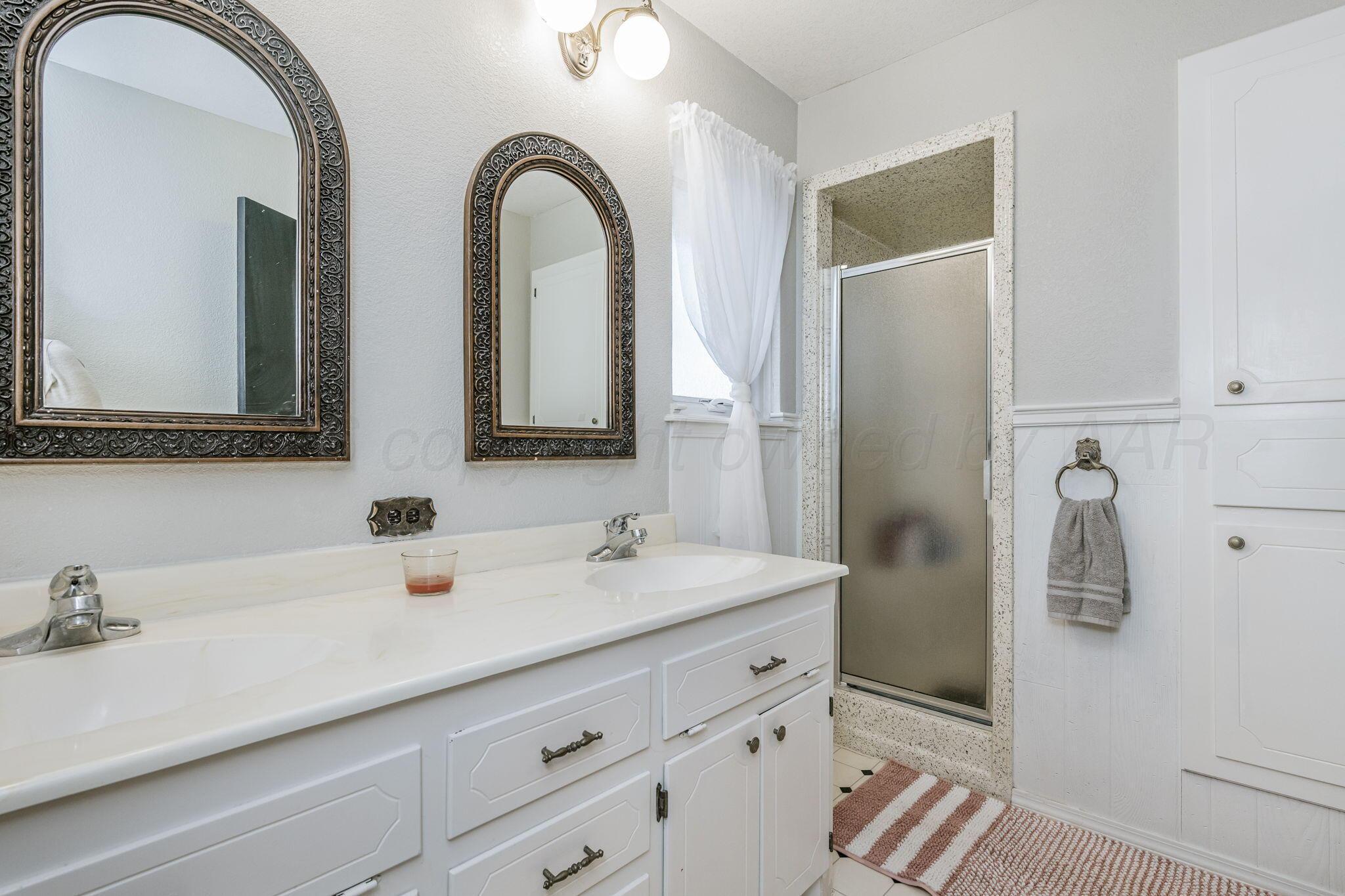 801 Arrah Friona, TX 79035 - Photo 19 of 37 a bathroom with a double vanity sink a mirror and shower