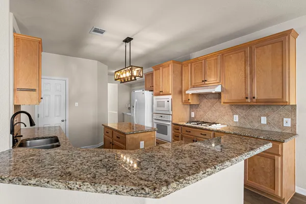 a kitchen with stainless steel appliances granite countertop a sink a stove and a wooden floors