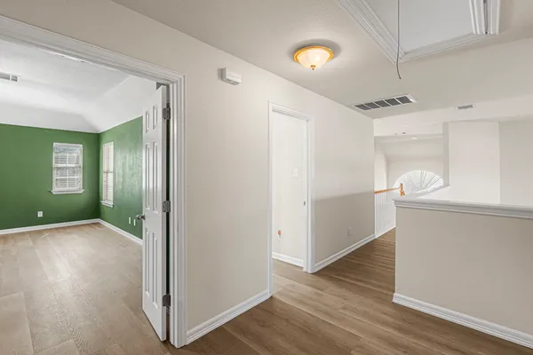 an empty room with wooden floor fan and windows
