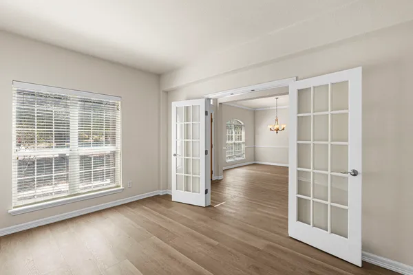 a view of an empty room with wooden floor and a window