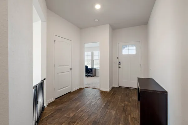 an empty room with wooden floor & windows